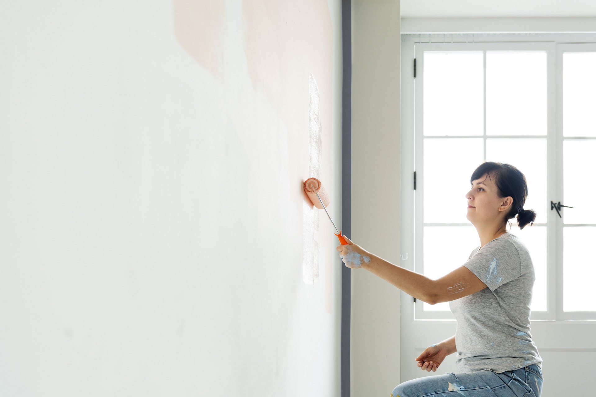 Woman painting the wall inside the house