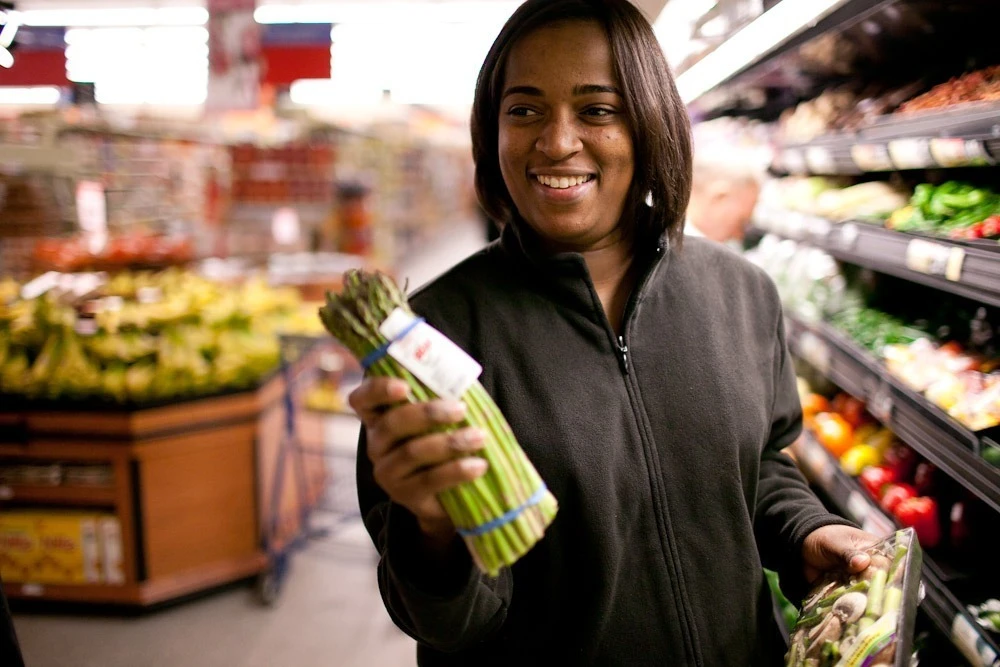 A woman holds asparagus in a grocery store